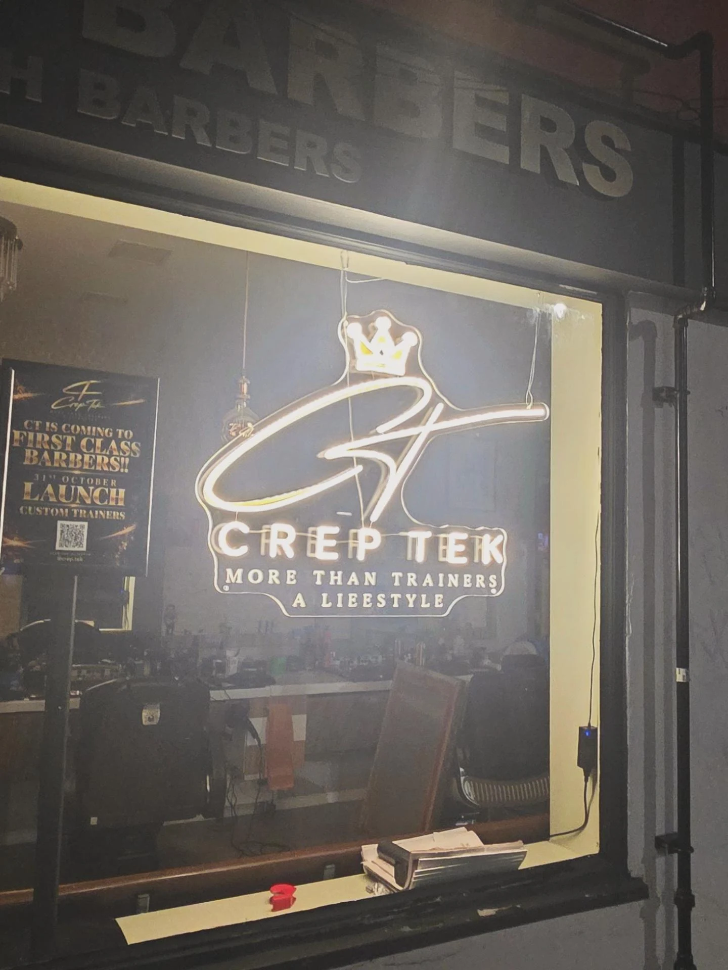 The illuminated CrepTek signature in the window at First Class Barbers, Whitstable